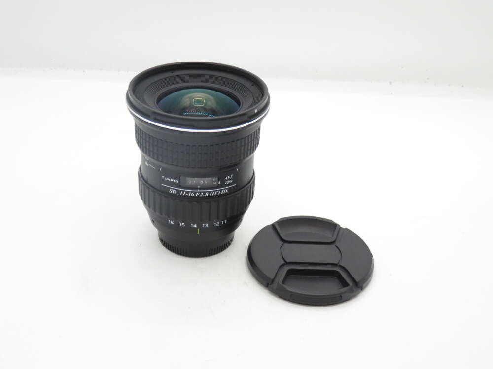 IMG_0562 Camera lens with lens cap on a white surface.