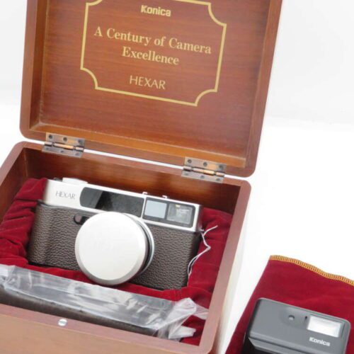 Konica Hexar camera in a wooden box with "A Century of Camera Excellence" text, accompanied by an external flash in a red velvet pouch.