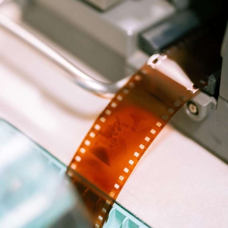 A strip of photographic film being processed in a film scanner or developer machine.
