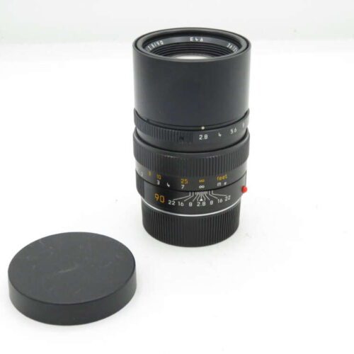 Camera lens with detachable cap placed beside it.