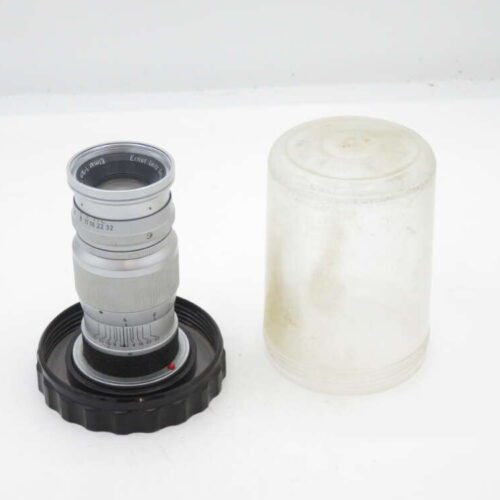 Silver camera lens with a black base, next to a translucent plastic cover.