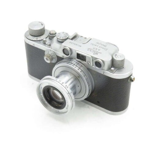 Vintage Leica rangefinder camera with a silver body and black leatherette covering, featuring a collapsible lens.