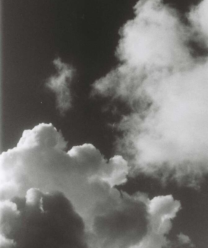 Black and white photo of large, fluffy clouds against a dark sky.