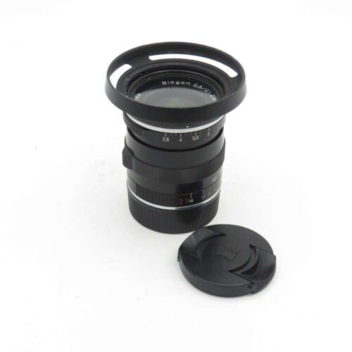 Camera lens with lens hood attached, next to a detached lens cap on a white background.
