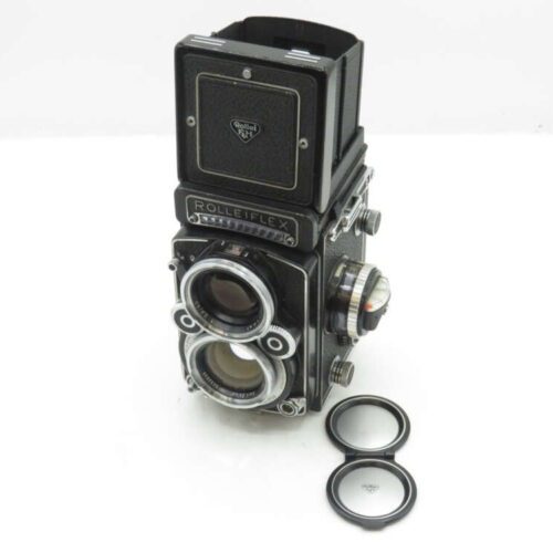 Vintage Rolleiflex twin-lens reflex camera with lens caps placed beside it.