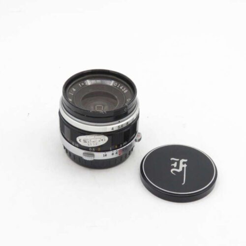 A 21mm f/4 camera lens with a detached lens cap on a white background.