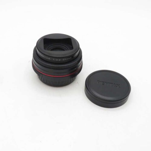 Pentax lens with a red ring and detached lens cap on a white background.
