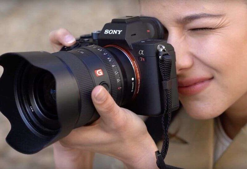 Person holding a Sony camera, aiming through the viewfinder.
