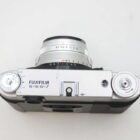Top view of a Fujifilm 6x6/6x7 medium format film camera showing the lens with aperture and focus markings, shutter speed dial, and other control knobs.