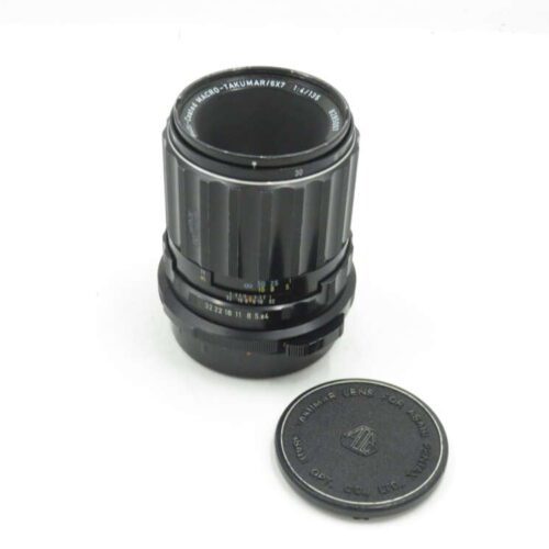 Asahi Macro-Takumar 1:4/135 camera lens with detached lens cap laying next to it.