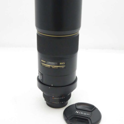 Nikon 300mm f/4 telephoto lens with lens cap on white background.