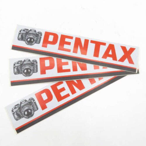 Three Pentax stickers featuring a black camera illustration and "PENTAX" in bold red letters with a black and red border.