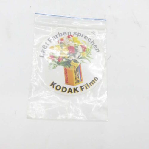 A transparent plastic bag containing an old Kodak label with a flower bouquet graphic and the text "laßt Farben sprechen" and "KODAK Filme".
