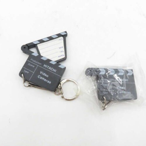 Two slate-shaped keychains labeled "Hitachi Video Cameras," one partially opened and the other in plastic packaging.