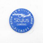 Blue round badge with the text "Over Ten Million Sold" at the top, "Stylus Cameras" in the center, and "Olympus" at the bottom.
