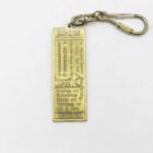 Gold-coloured Expo '85 keychain with engraved text and a clip attachment.