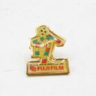 Fuji Film World Cup 1990 official pin featuring a stylised footballer in green, yellow, and red colours.