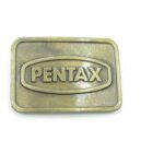 Rectangular brass belt buckle with the word "PENTAX" in raised letters inside an oval border.