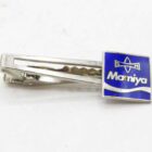 Silver tie clip with a blue square emblem featuring the word "Mamiya" and a compass-like logo.