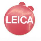 Red circular badge with the word "LEICA" in white capital letters.