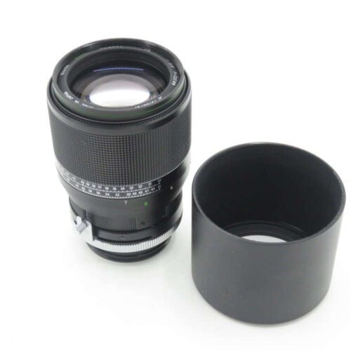 A black camera lens with a detached lens hood placed next to it.