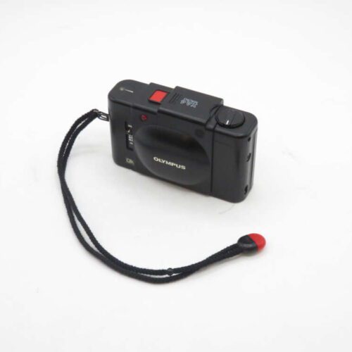 Black Olympus XA film camera with wrist strap, viewed from above on a white background.