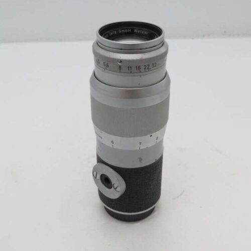 Silver and black camera lens with engraved markings, featuring the text "Ernst Leitz GmbH Wetzlar" around the top and a focus dial.