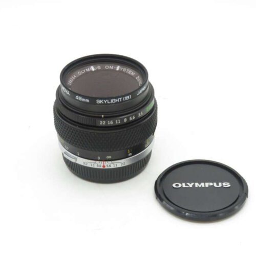 Olympus camera lens with the cap placed beside it.