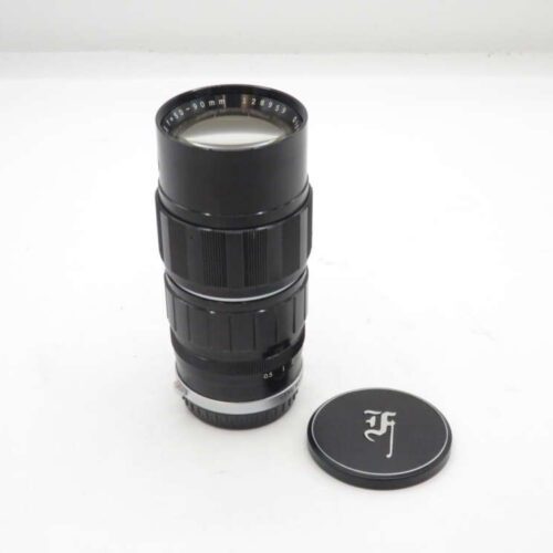 Black camera lens with an attached lens cap, placed next to a separate lens cap on a white surface.