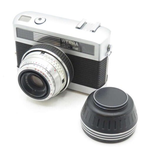 Vintage Werra camera with lens cap removed, placed beside it on a white surface.