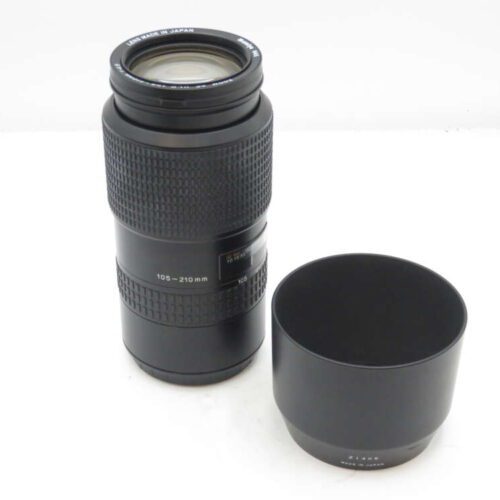 Camera zoom lens marked 105-210mm next to a lens hood.