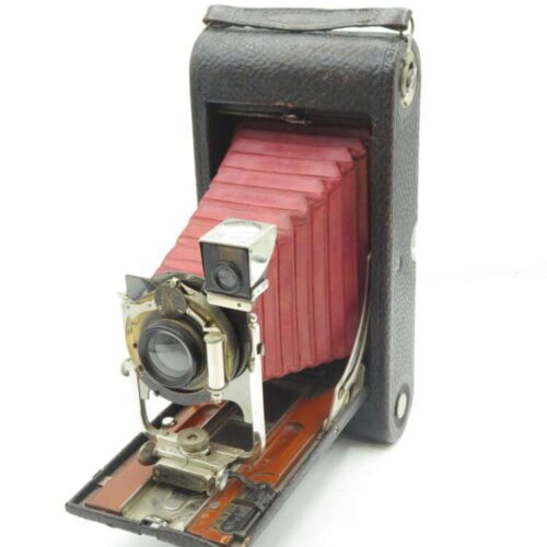 Vintage folding bellows camera with a red leather bellows and black textured body.