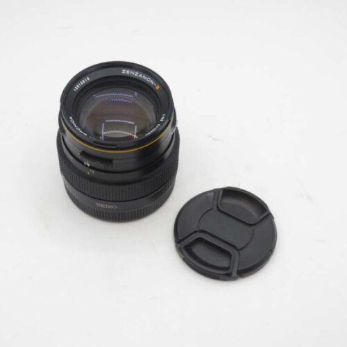 Camera lens with a removed cap placed beside it.