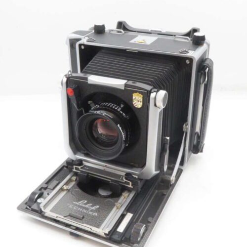 Vintage large format camera with bellows and front standard extended, displaying brand logo and lens.