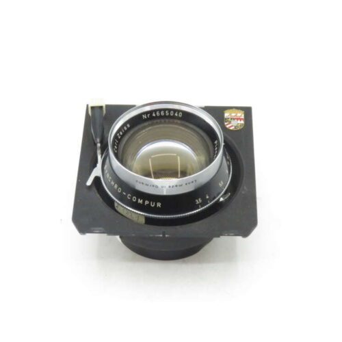 Vintage Synchro-Compur camera lens on a black mounting board.