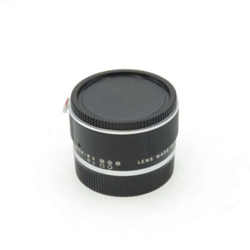 Black camera lens with a silver ring, lens cap on, and text "Lens Made" partially visible.