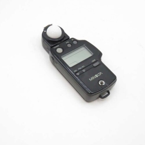 A digital Minolta light meter with an LCD screen and buttons, featuring a dome sensor on the top.