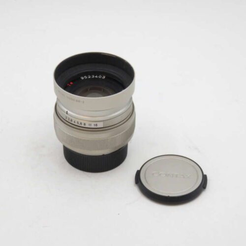 A silver camera lens with a matching lens cap placed beside it on a white background.