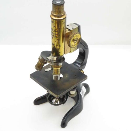 A vintage brass and black metal microscope with dual eyepieces and a flat rectangular stage.