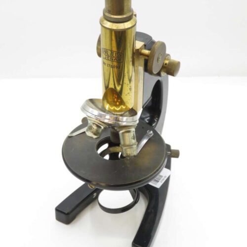 Vintage brass and black microscope with a round base and adjustable knobs.
