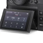 Close-up of a camera's tilting touchscreen display showing settings and buttons such as ISO, shutter speed, and aperture.