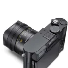 A black Leica camera with a lens displaying focal length markings and a macro setting.