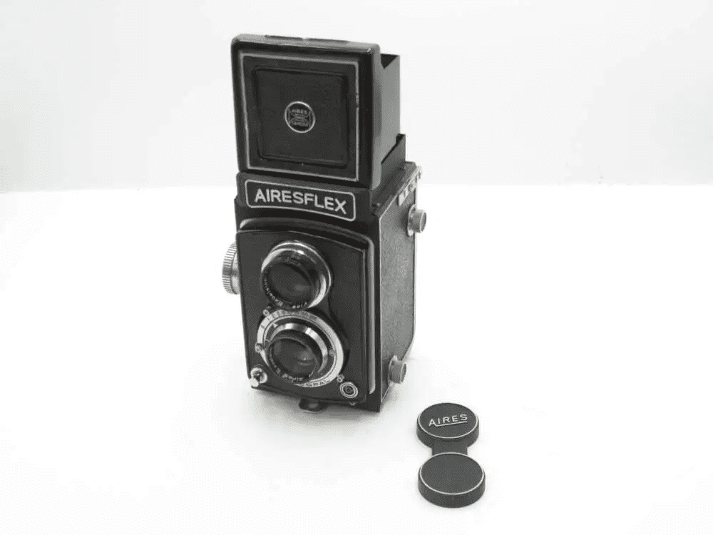 Vintage Airesflex twin-lens reflex camera with lens caps on a white background.