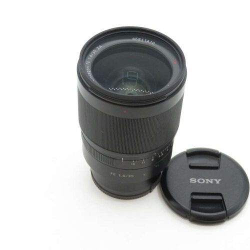A Sony camera lens with a lens cap placed beside it.