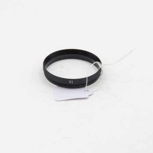 A black circular lens adapter with "VI" printed on it, attached to a white tag by a string.