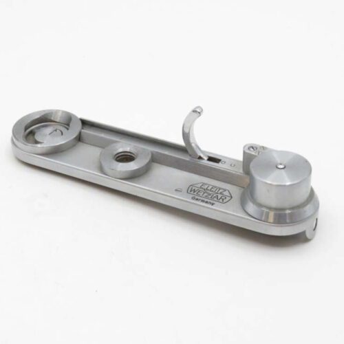 Silver Leica camera winder base plate on a white background.