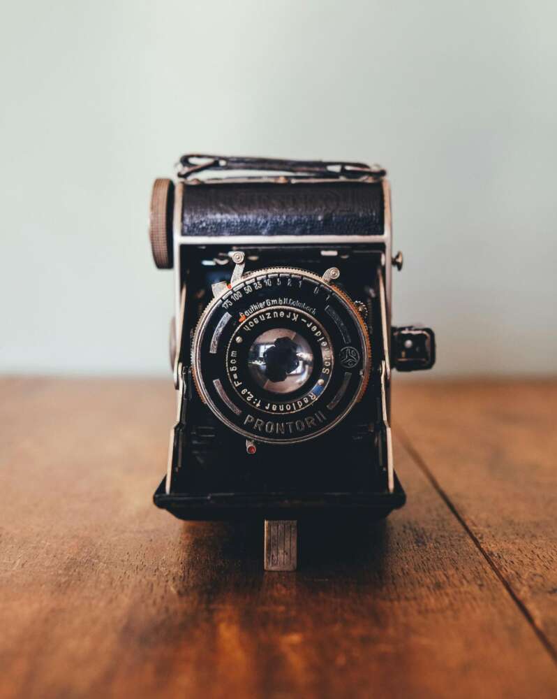 Vintage folding camera on a wooden table.