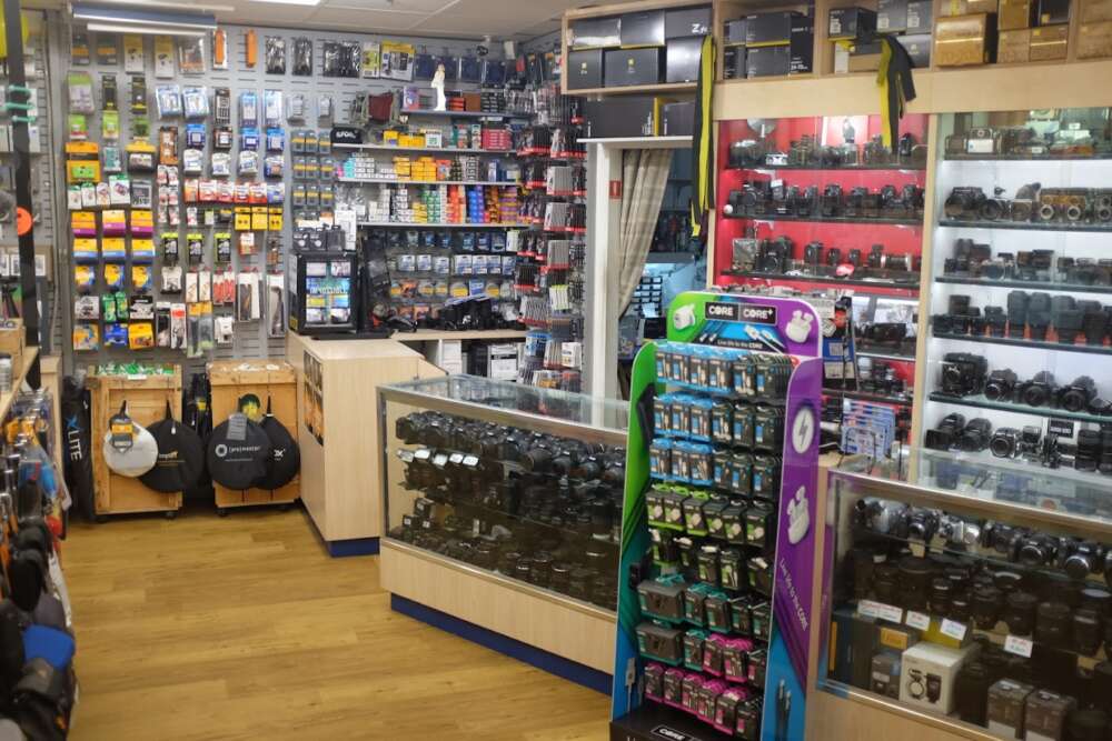 Camera and accessories store interior with shelves displaying cameras, lenses, and various equipment.