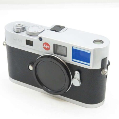 Leica M8 digital rangefinder camera with a black lens cap on a white surface.