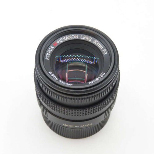 A Konica Hexanon 50mm F2 camera lens, showing the front glass element and markings around the lens barrel against a white background.